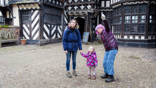 Family exploring the courtyard of the house at Little Moreton Hall, Cheshire
